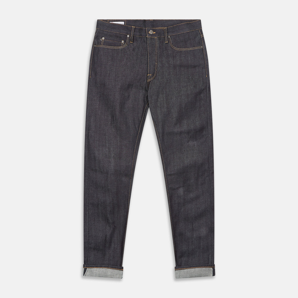 A pair of Turnbull & Asser Indigo Japanese Selvedge Denim Jeans in dark blue with rolled-up cuffs, yellow stitching, five pockets, and a button fly, laid flat on a white background.