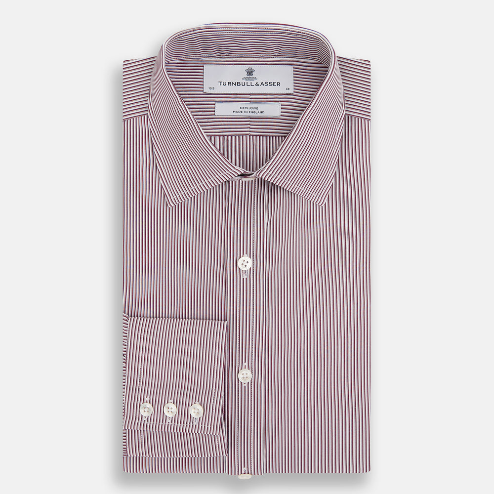 The Turnbull & Asser Burgundy Shadow Stripe Mayfair Shirt is a long-sleeved button-up with thin vertical burgundy stripes, classic collar, and buttoned cuffs, shown laid flat on a white background.