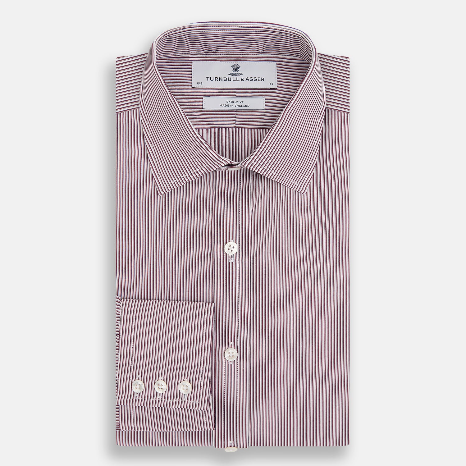 View 5 of product The Turnbull & Asser Burgundy Shadow Stripe Mayfair Shirt is a long-sleeved button-up with thin vertical burgundy stripes, classic collar, and buttoned cuffs, shown laid flat on a white background.