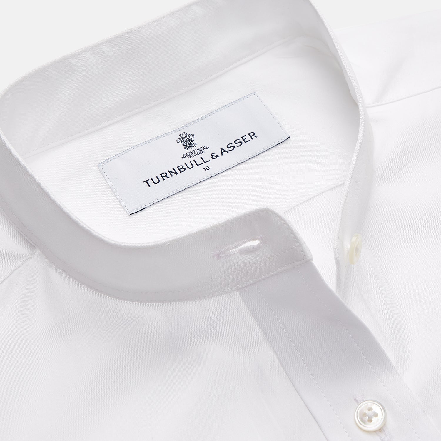 View 2 of product The White Cotton Lauren Shirt by Turnbull & Asser, featuring a stand collar, button-down front, and elongated body, is laid flat on a plain white background.
