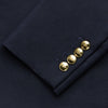 View 4 of product The Turnbull & Asser Navy Plain Wool Single Breasted Blazer, with brass front and cuff buttons and an asymmetric pocket design, is shown laid flat on a white background.