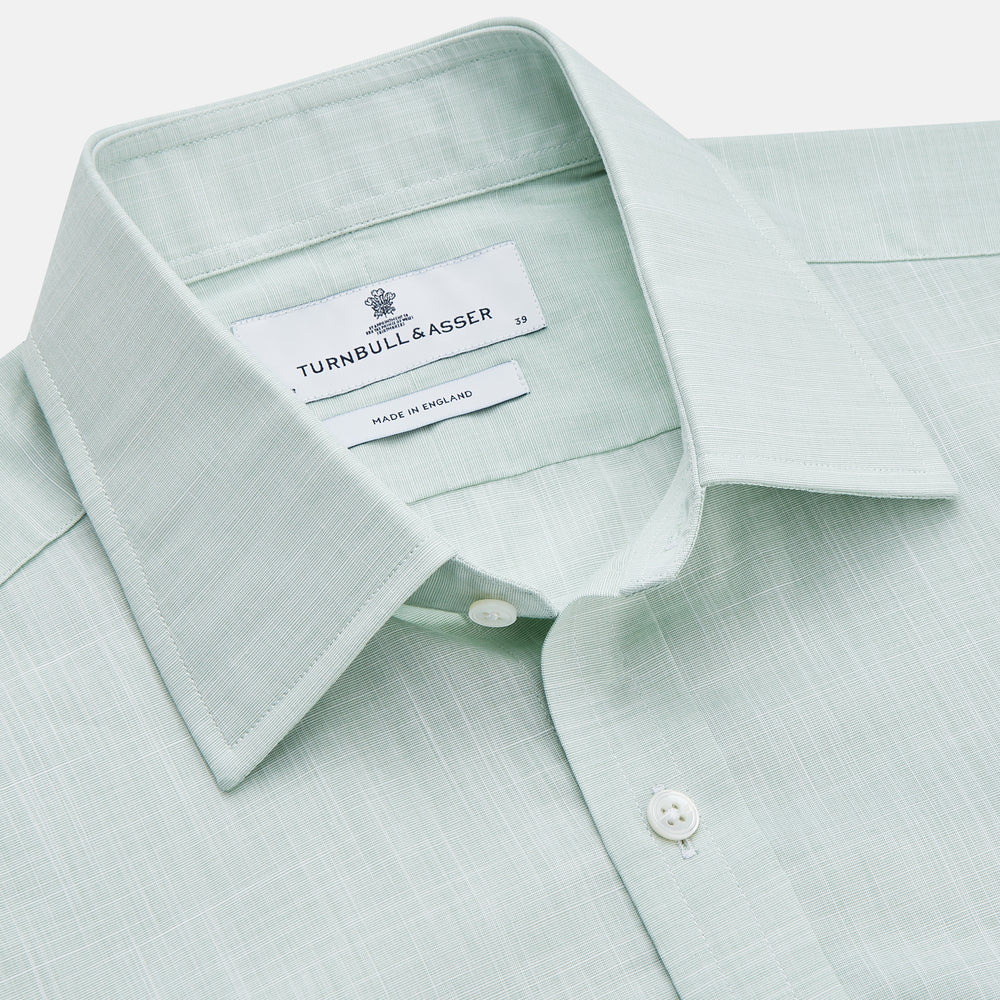 The Turnbull & Asser Light Green Chambray Regular Fit Mayfair Shirt for men features long sleeves, a collar, white buttons, and buttoned cuffs, displayed flat on a white background.
