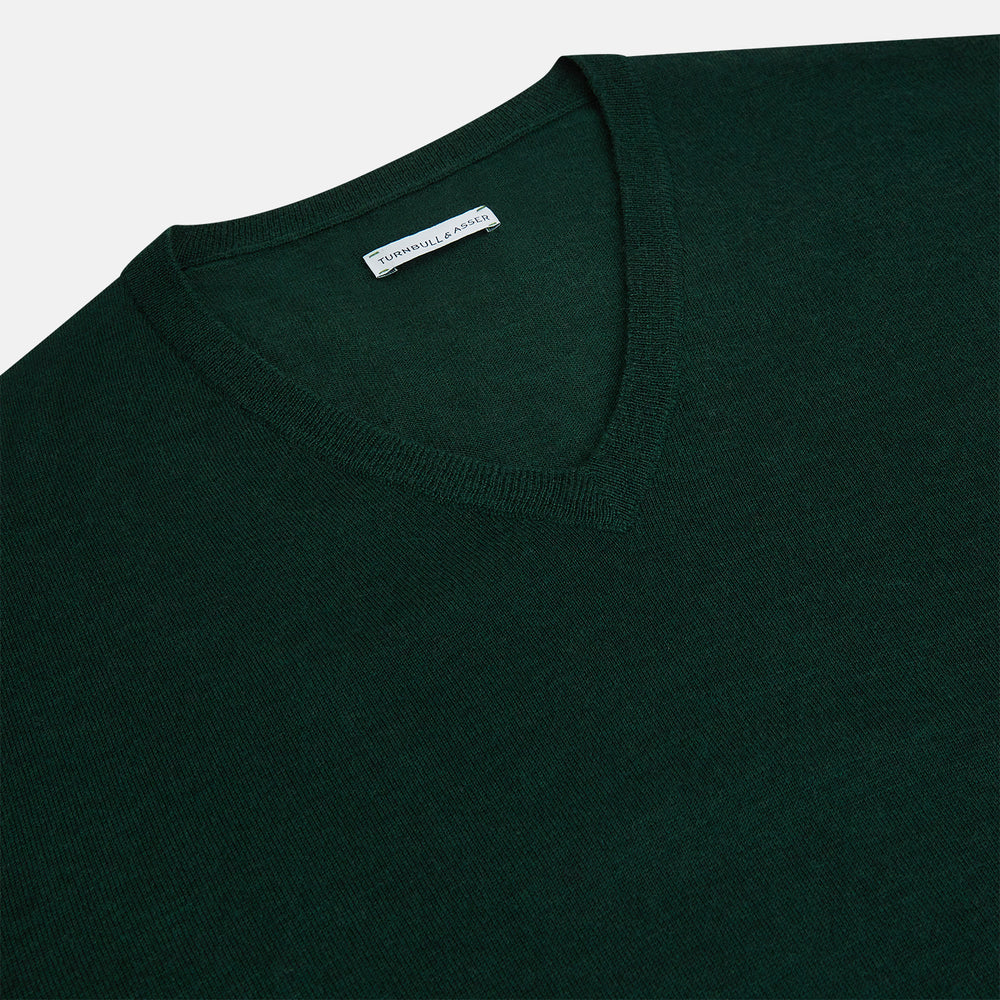 The Turnbull & Asser Petrol Green Merino V-Neck Jumper features long sleeves and ribbed cuffs and hem—an essential knitwear piece, shown against a white background.