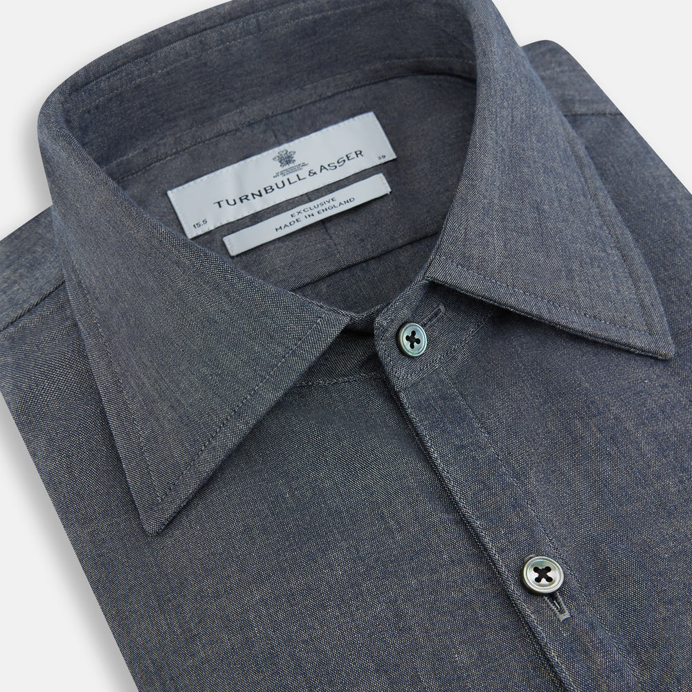 The Turnbull & Asser Azzurro Westminster Shirt in dark grey features long sleeves, a classic collar, buttoned cuffs, and a straight hem, showcased against a white background, highlighting refined British craftsmanship.