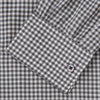 View 4 of product A person with a shaved head models the Turnbull & Asser Grey Check Weekend Fit Flannel Shirt with a Derby collar and 1-button cuffs, sleeves rolled up, paired with dark trousers against a plain background, gazing directly at the camera.