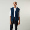 View 3 of product A man with a shaved head wears a Turnbull & Asser Navy Sleeveless Cashmere Cardigan over a white dress shirt with rolled-up sleeves and dark trousers, standing against a plain light gray background.