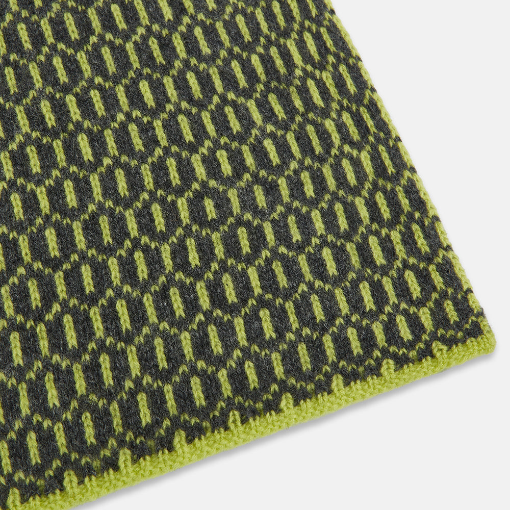 The Turnbull & Asser Graphite and Chartreuse Lemon Hexagon Cashmere Knitted Scarf features a geometric pattern in green and yellow tones, neatly folded to show both ends—an essential accessory with luxurious softness.