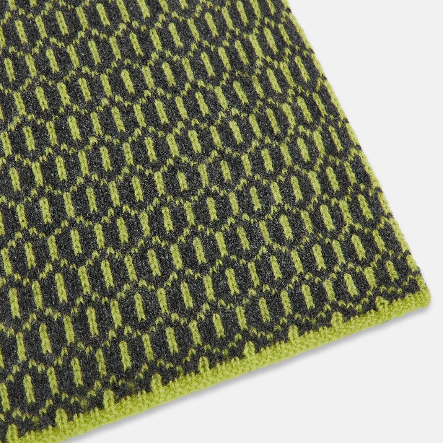 View 2 of product The Turnbull & Asser Graphite and Chartreuse Lemon Hexagon Cashmere Knitted Scarf features a geometric pattern in green and yellow tones, neatly folded to show both ends—an essential accessory with luxurious softness.
