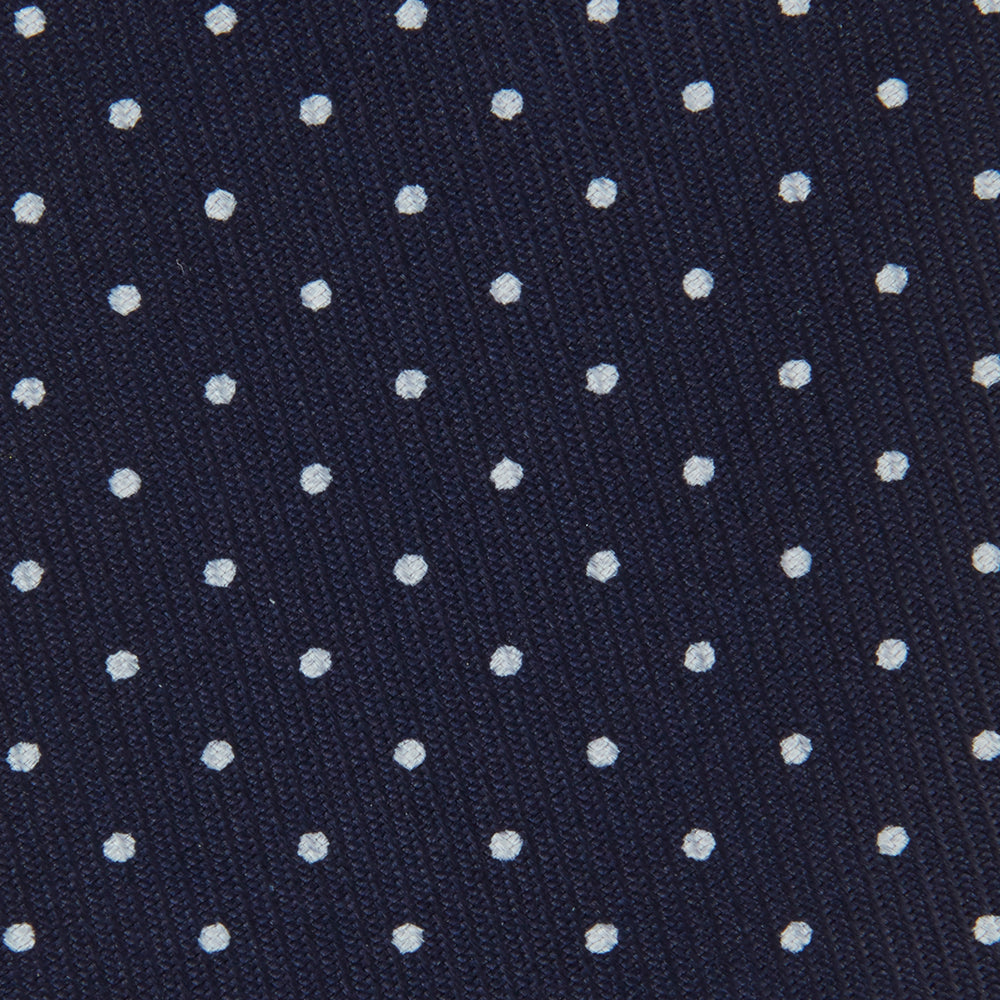 The Turnbull & Asser White and Navy Spot Printed Silk Tie, shown rolled with its pointed end forward on a white background, is an elegant accessory that pairs perfectly with a crisp shirt for smart occasions.