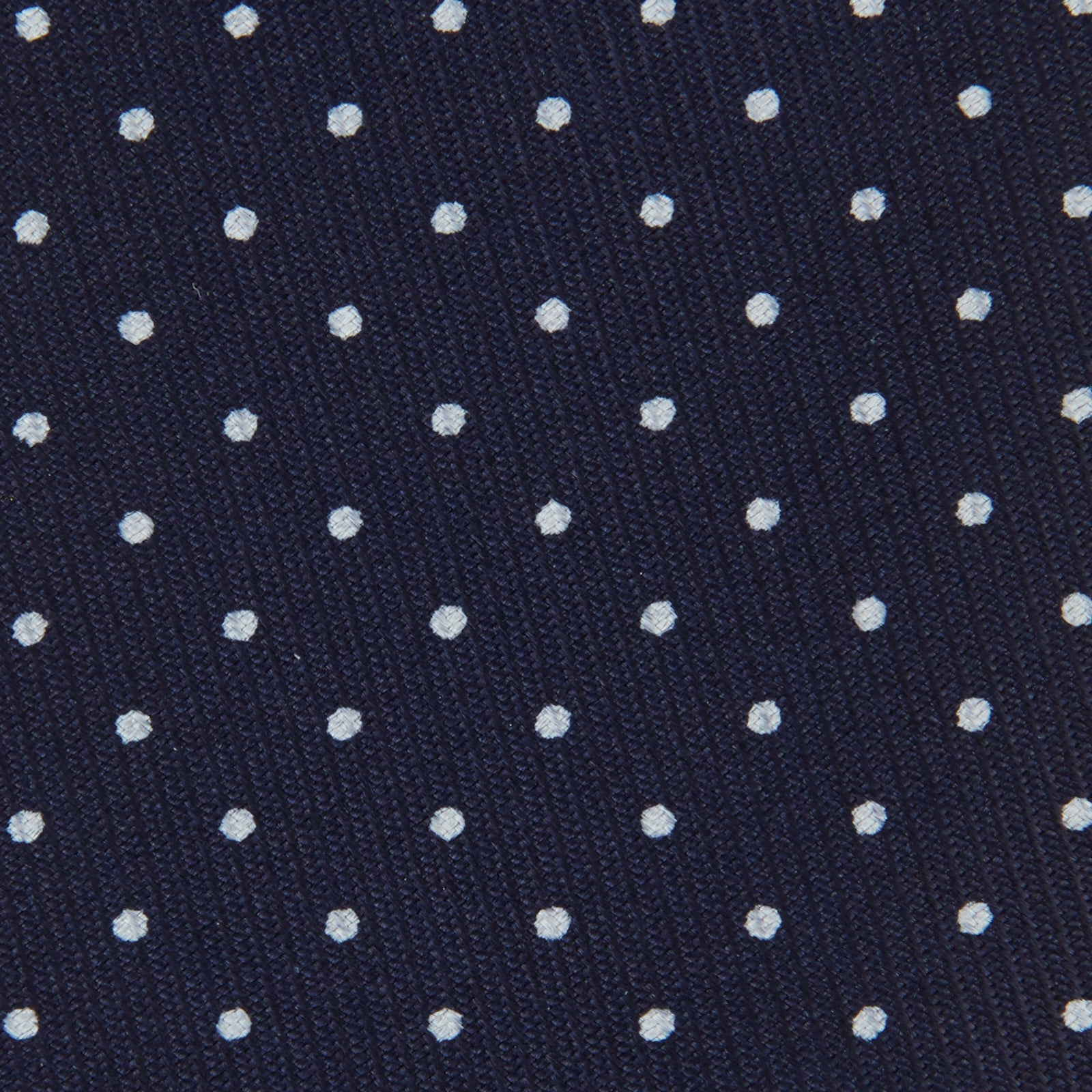 View 3 of product The Turnbull & Asser White and Navy Spot Printed Silk Tie, shown rolled with its pointed end forward on a white background, is an elegant accessory that pairs perfectly with a crisp shirt for smart occasions.
