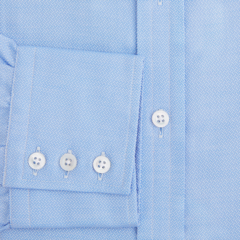 The Blue Herringbone Mayfair Shirt by Turnbull & Asser features light blue and white stripes, long sleeves, a classic collar, white buttons, and buttoned cuffs. Shown on a plain white background, it's perfect for formal occasions.