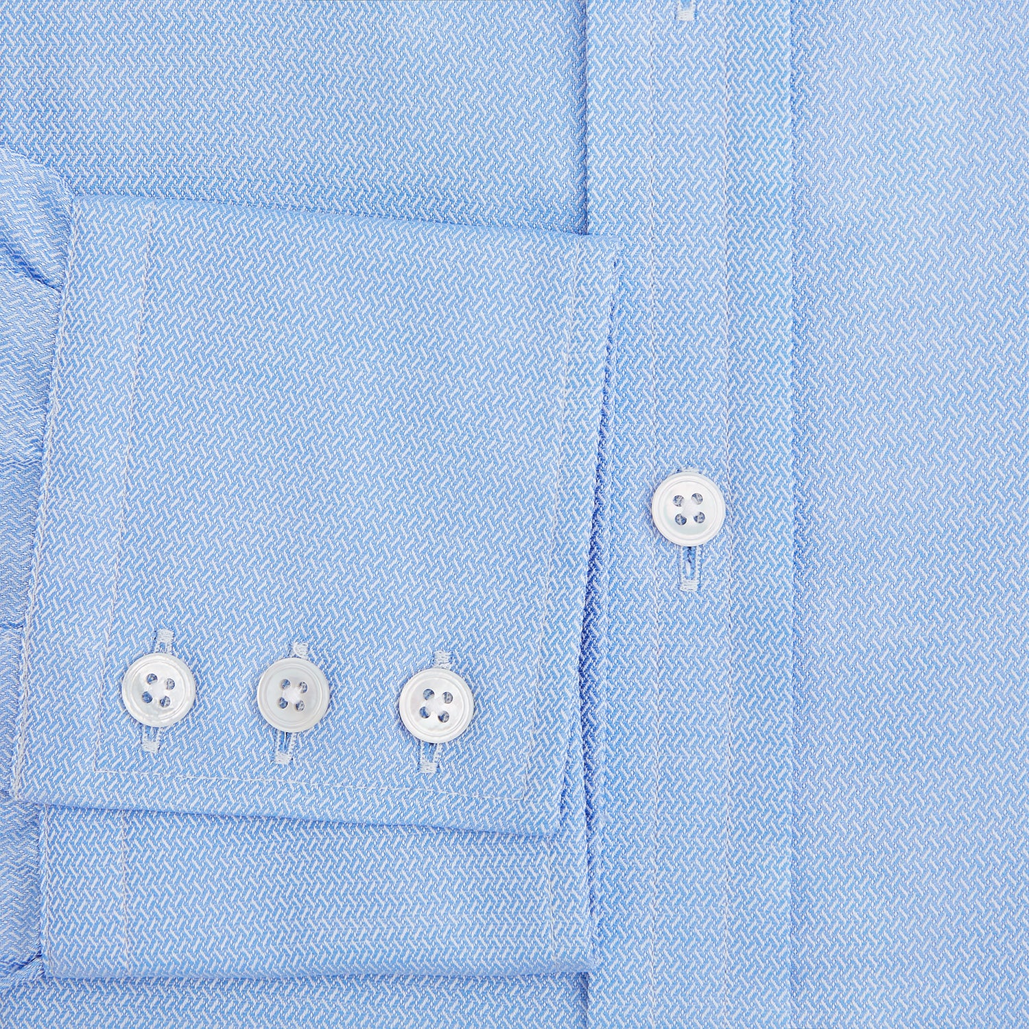 View 4 of product The Blue Herringbone Mayfair Shirt by Turnbull & Asser features light blue and white stripes, long sleeves, a classic collar, white buttons, and buttoned cuffs. Shown on a plain white background, it's perfect for formal occasions.