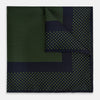 View 1 of product The Turnbull & Asser Navy and Kelly Green Dot Silk Pocket Square features small green dots on navy silk and a folded corner displaying the reverse—an elegant, handmade accessory perfect for enhancing any formal attire.