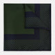 The Turnbull & Asser Navy and Kelly Green Dot Silk Pocket Square features small green dots on navy silk and a folded corner displaying the reverse—an elegant, handmade accessory perfect for enhancing any formal attire.