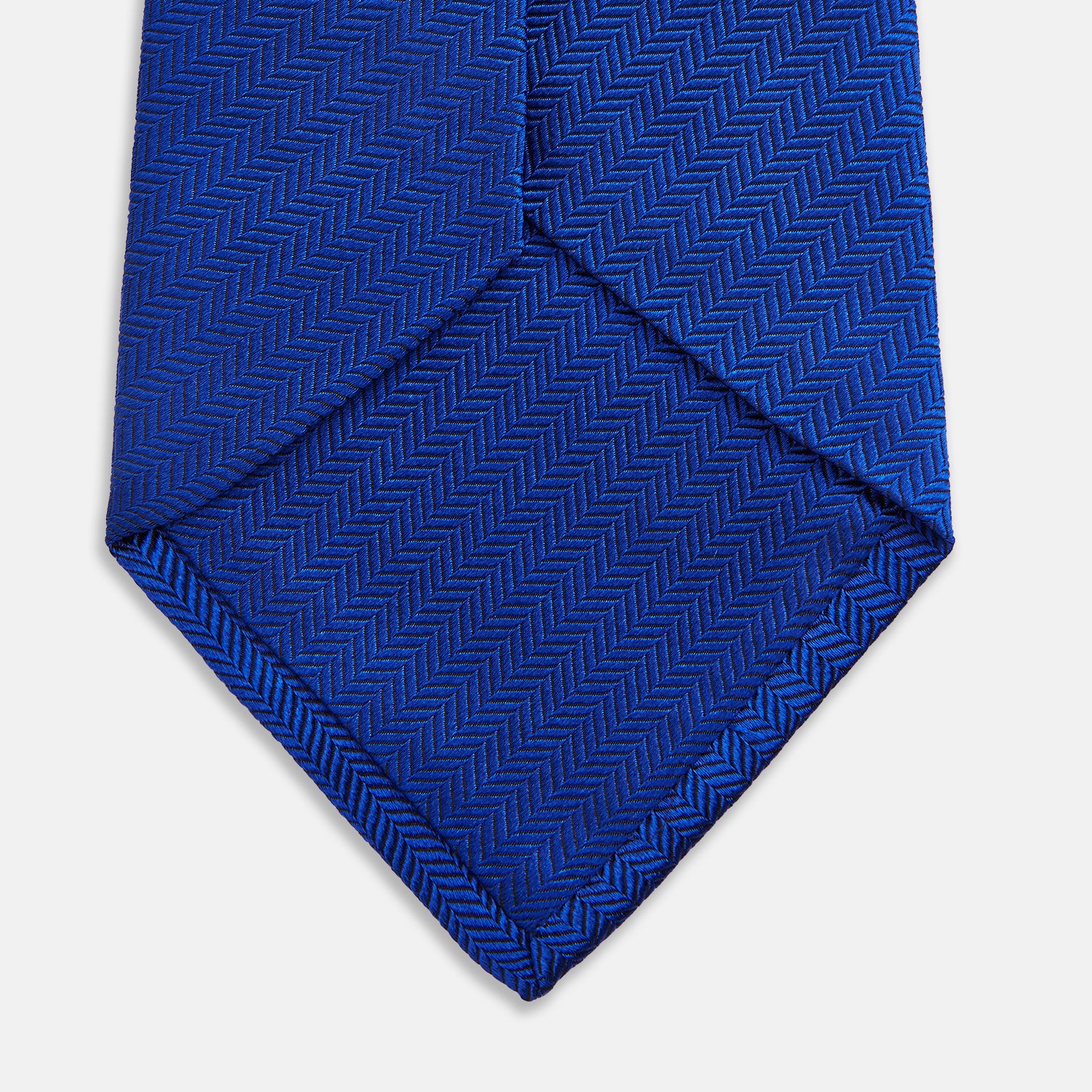 View 4 of product The Turnbull & Asser Plain Herringbone Cruise Tie in bright blue, shown rolled up on a white background, features a subtle chevron pattern—an essential finishing touch for your smart look.