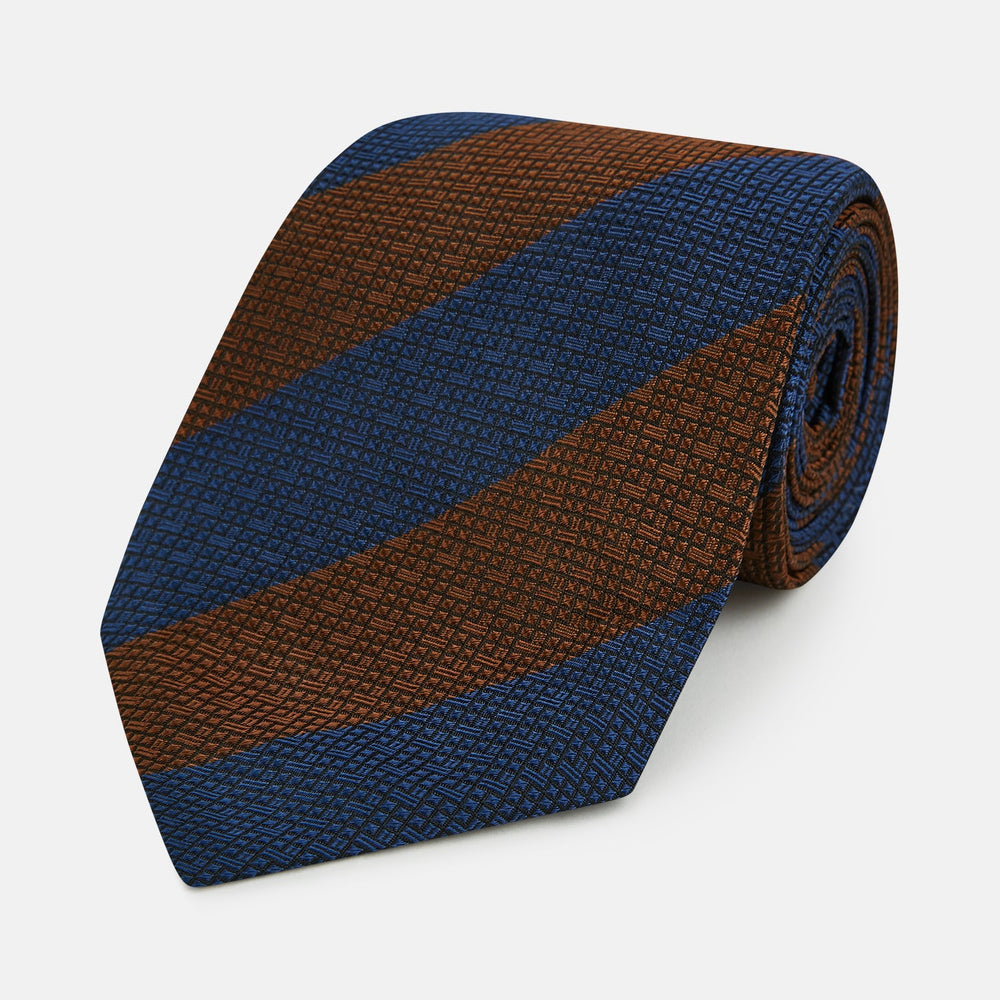 A close-up of the Turnbull & Asser Brown and Navy Block Stripe Silk Tie displays its textured pattern with classic suiting diagonal stripes in navy blue and brown on a light background.