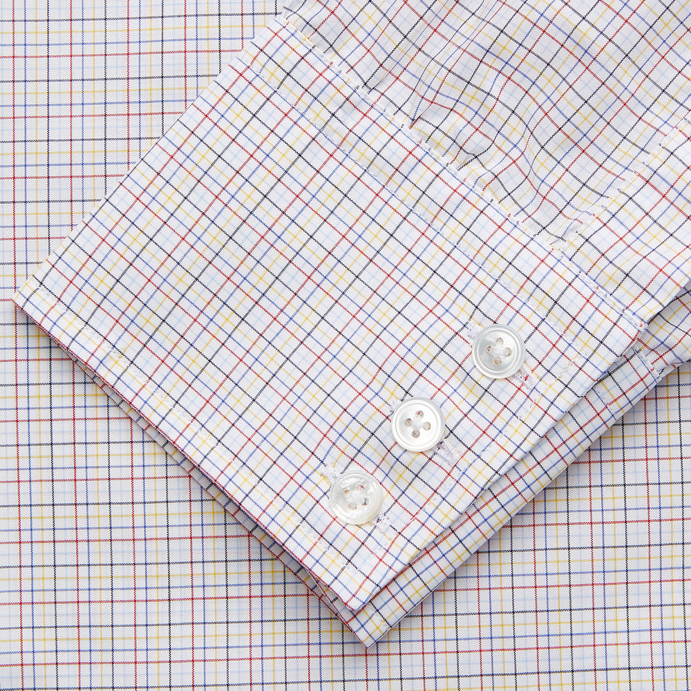 A man stands against a beige background, facing forward with a neutral expression and arms relaxed, wearing the Turnbull & Asser Red Multi Check Regular Fit Mayfair Shirt.