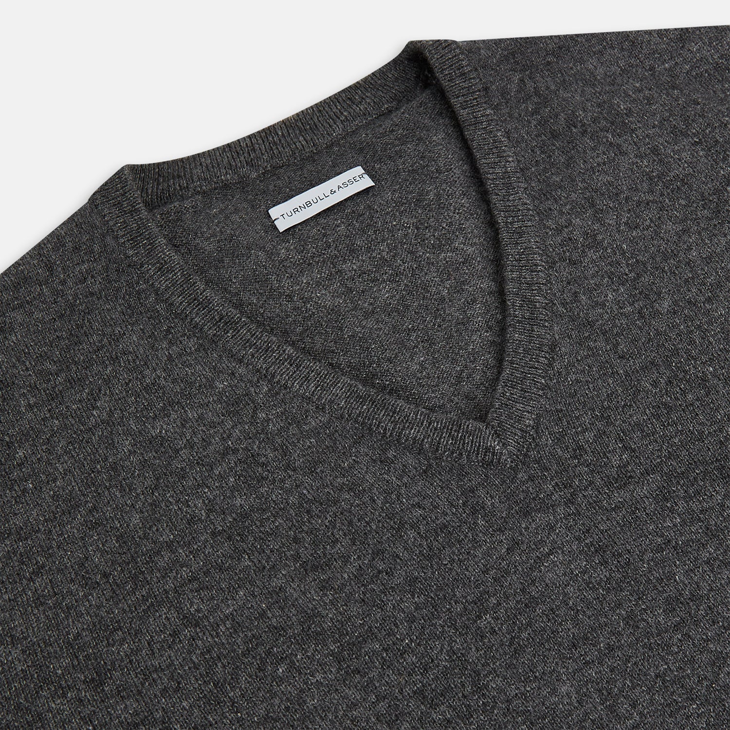 View 2 of product The Charcoal Grey Cashmere V-neck Jumper by Turnbull & Asser features ribbed cuffs, hem, and neckline—an essential knitwear piece, shown on a white background.