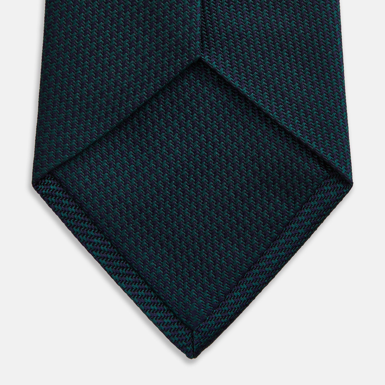 View 4 of product The Turnbull & Asser Navy Houndstooth Forest Green Tie is shown rolled up, featuring a subtle houndstooth pattern against a plain white background.