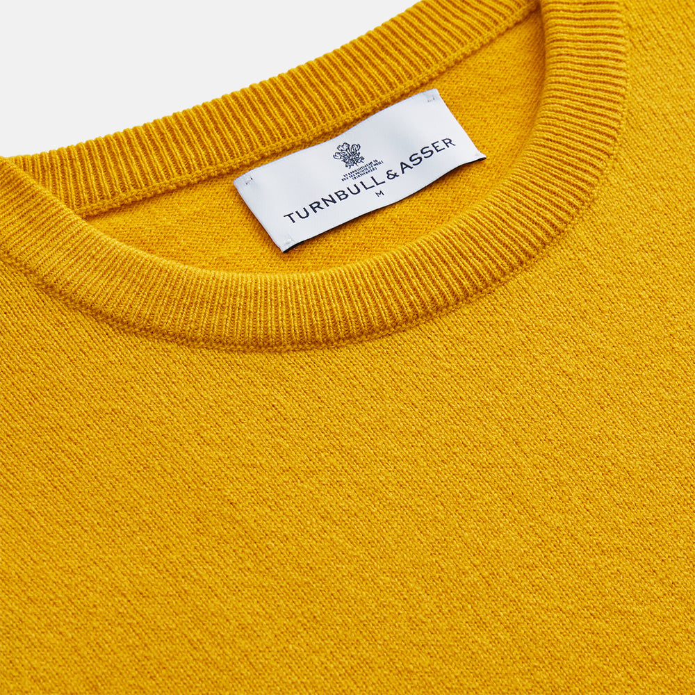 The Gold Glenn Cashmere Crew Neck Jumper by Turnbull & Asser is a luxurious, long-sleeved knit in vibrant mustard yellow, shown laid flat on a white background—an eye-catching essential.