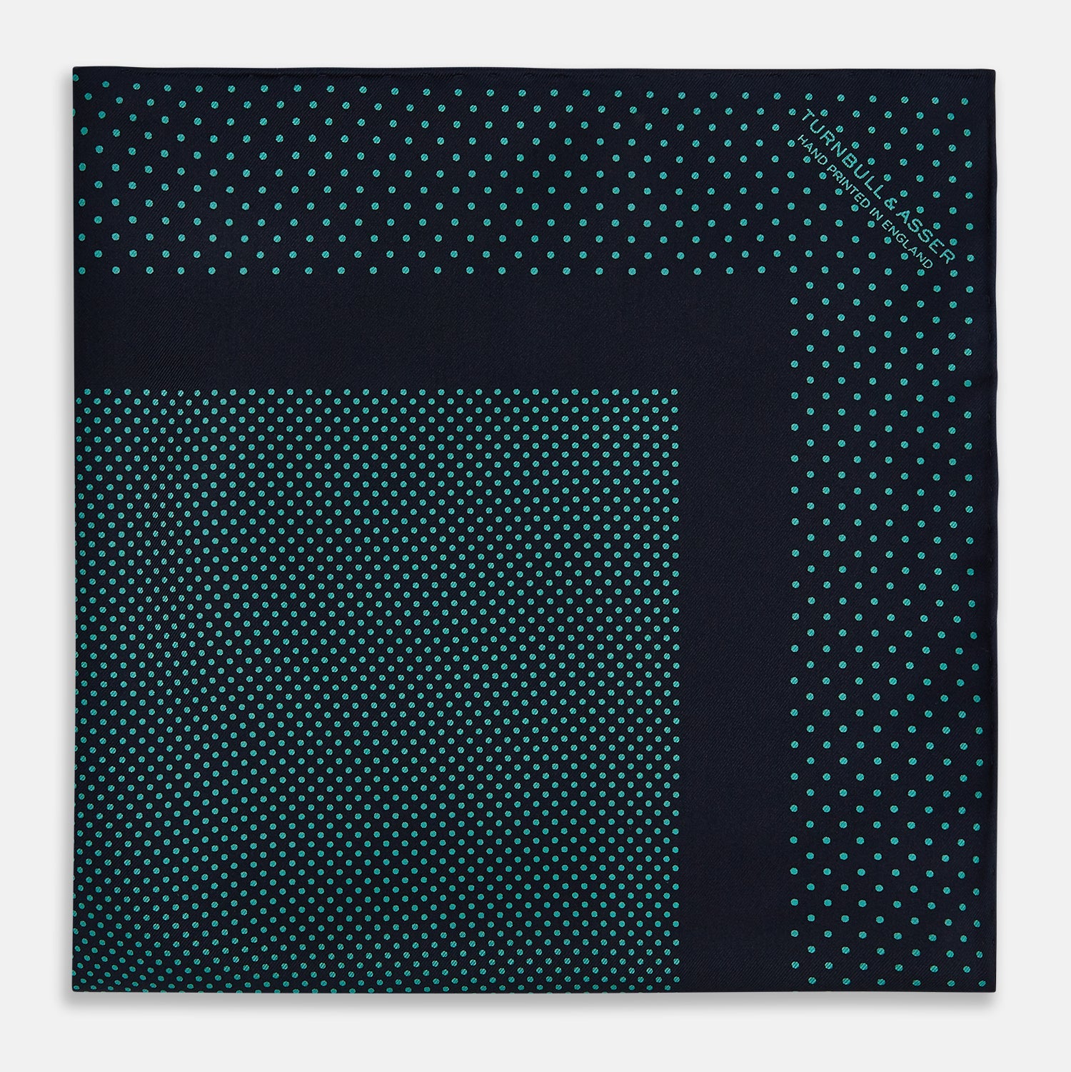 View 4 of product The Turnbull & Asser Navy and Petrol Green Dot Silk Pocket Square features handmade craftsmanship with petrol green polka dots and a darker border, elegantly displayed on a white background.