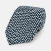 View 1 of product The Turnbull & Asser Navy Flower Patterned Silk Tie is shown rolled up, displaying a repeating floral design with small white and light blue circles on navy, set against a plain white background.