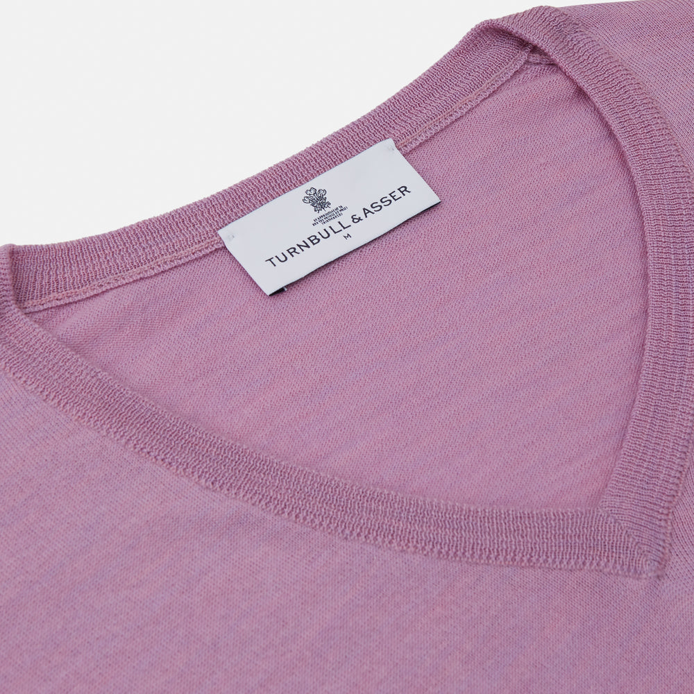 The Pink Merino Kennedy V-Neck Jumper by Turnbull & Asser features long sleeves with ribbed cuffs and waistband, shown on a plain white background—ideal for knitwear lovers.