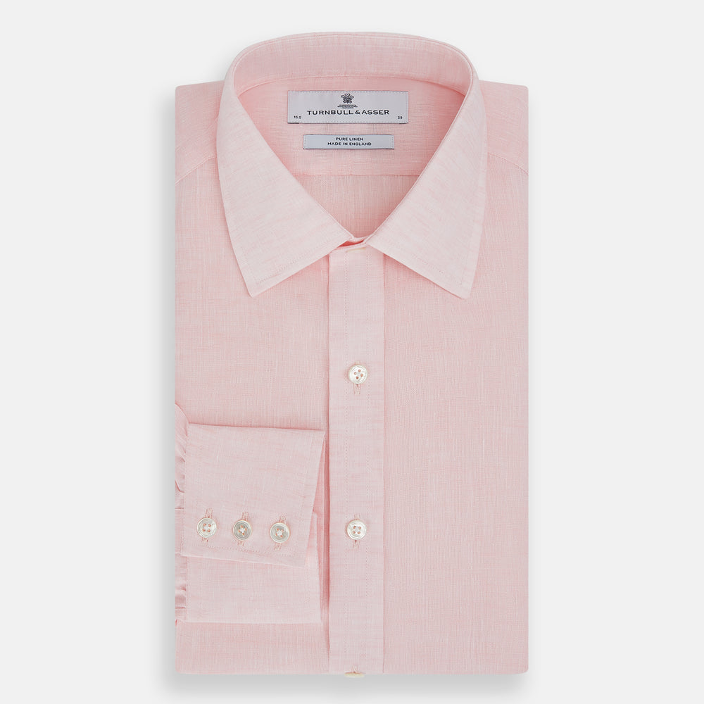 The Turnbull & Asser Pale Pink Linen Mayfair Shirt features a classic, formal style with long sleeves, a collar, and white buttons. Shown laid flat on a white background.