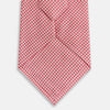 View 3 of product The Turnbull & Asser Pink and White Houndstooth Silk Tie features a small pattern and is displayed rolled up on a plain white background, making it perfect for pairing with any office shirt.