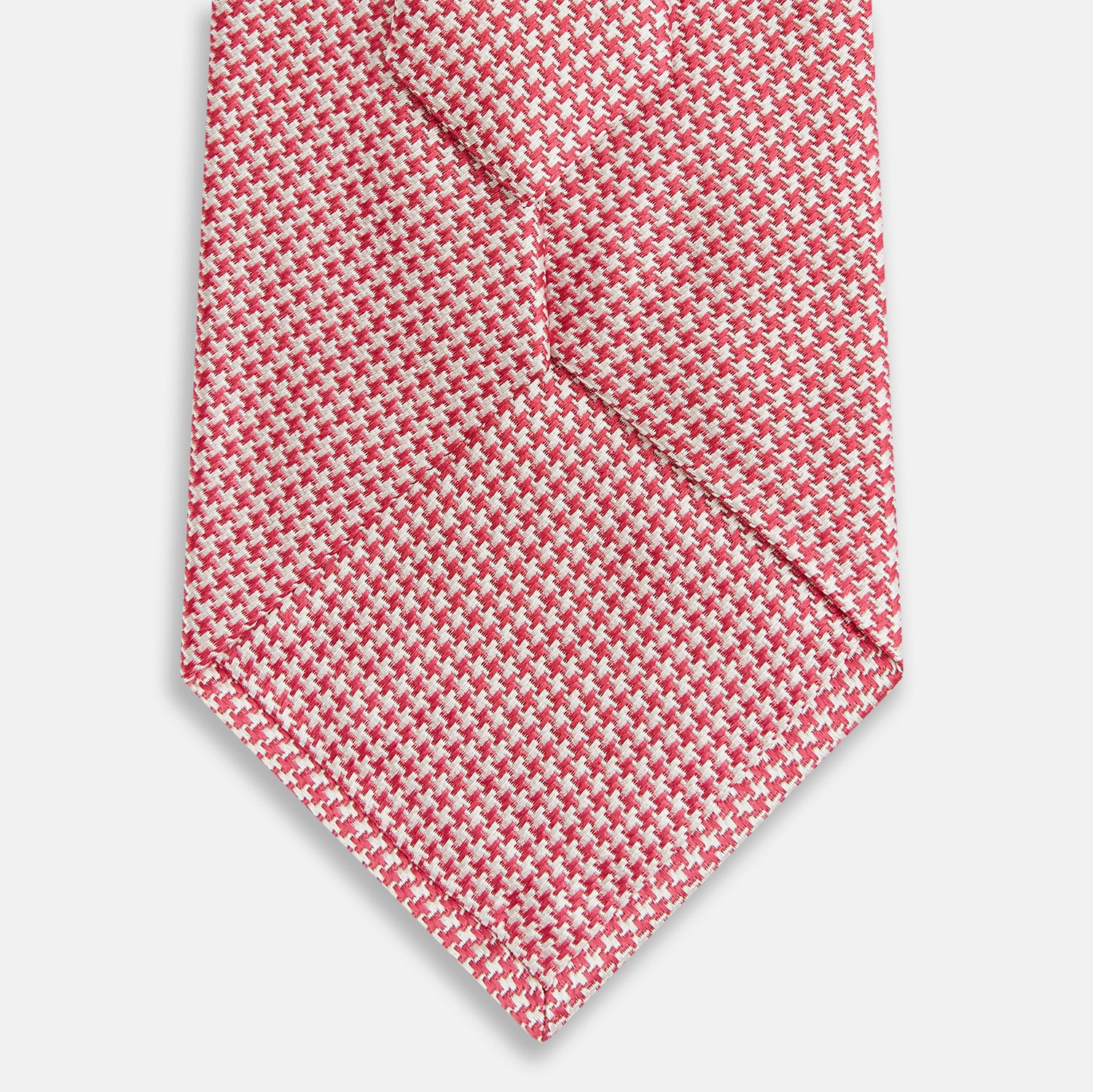 View 3 of product The Turnbull & Asser Pink and White Houndstooth Silk Tie features a small pattern and is displayed rolled up on a plain white background, making it perfect for pairing with any office shirt.