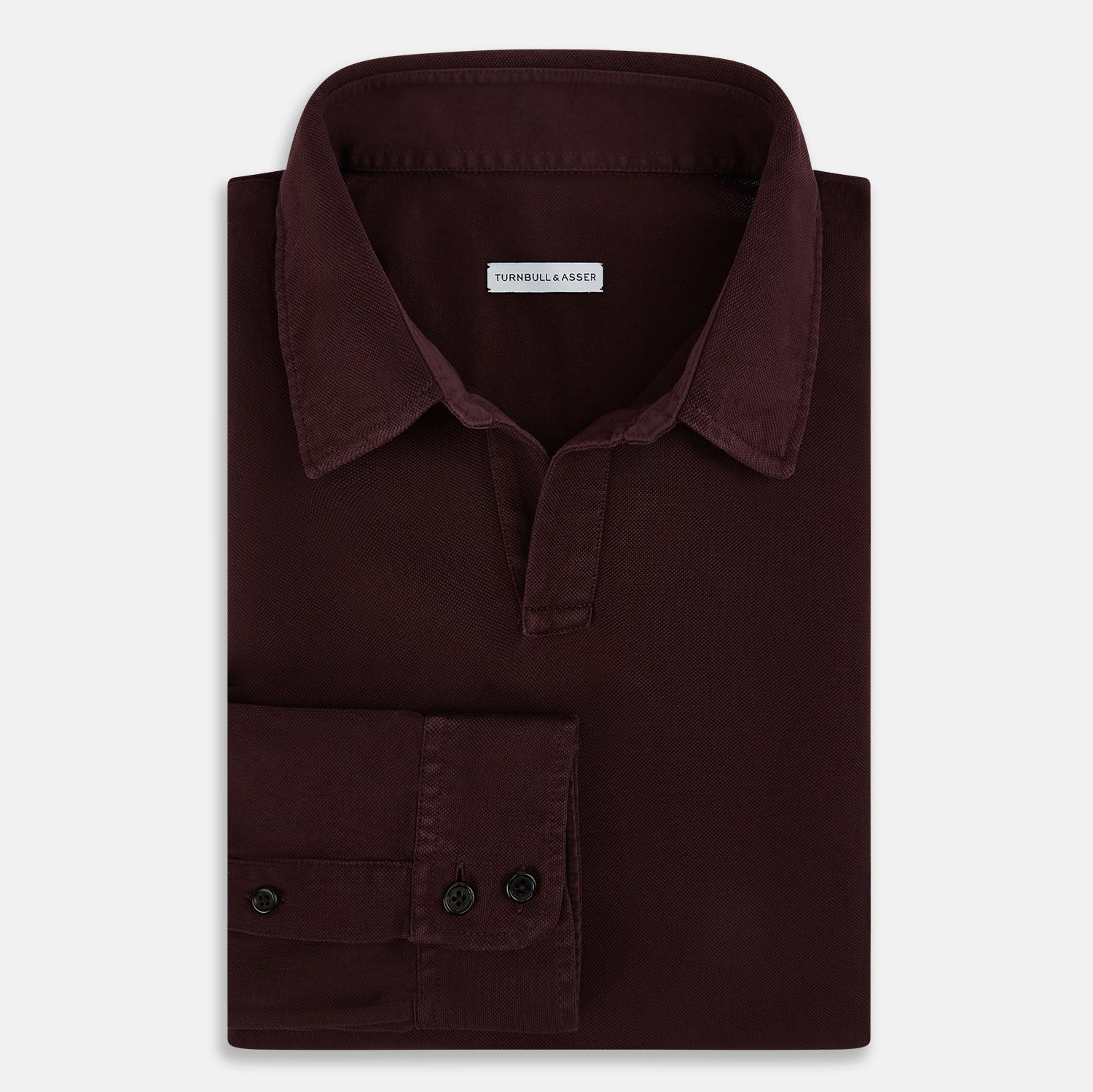 View 5 of product The Turnbull & Asser Burgundy Rugby Polo Shirt is a long-sleeve, pure cotton collared top with no visible buttons, shown laid flat on a white background.