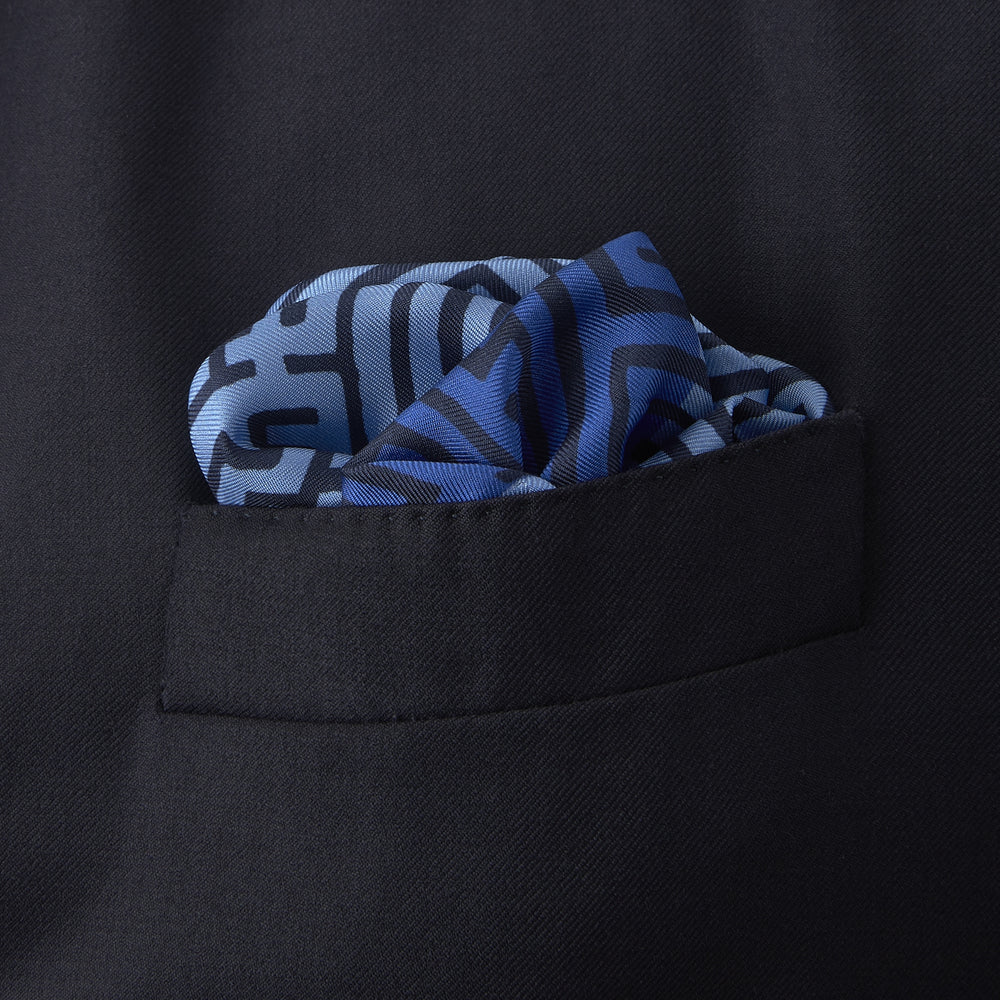 The Blue Maze Silk Pocket Square by Turnbull & Asser features a geometric maze-inspired pattern and central logo, with a folded corner for an artful touch.