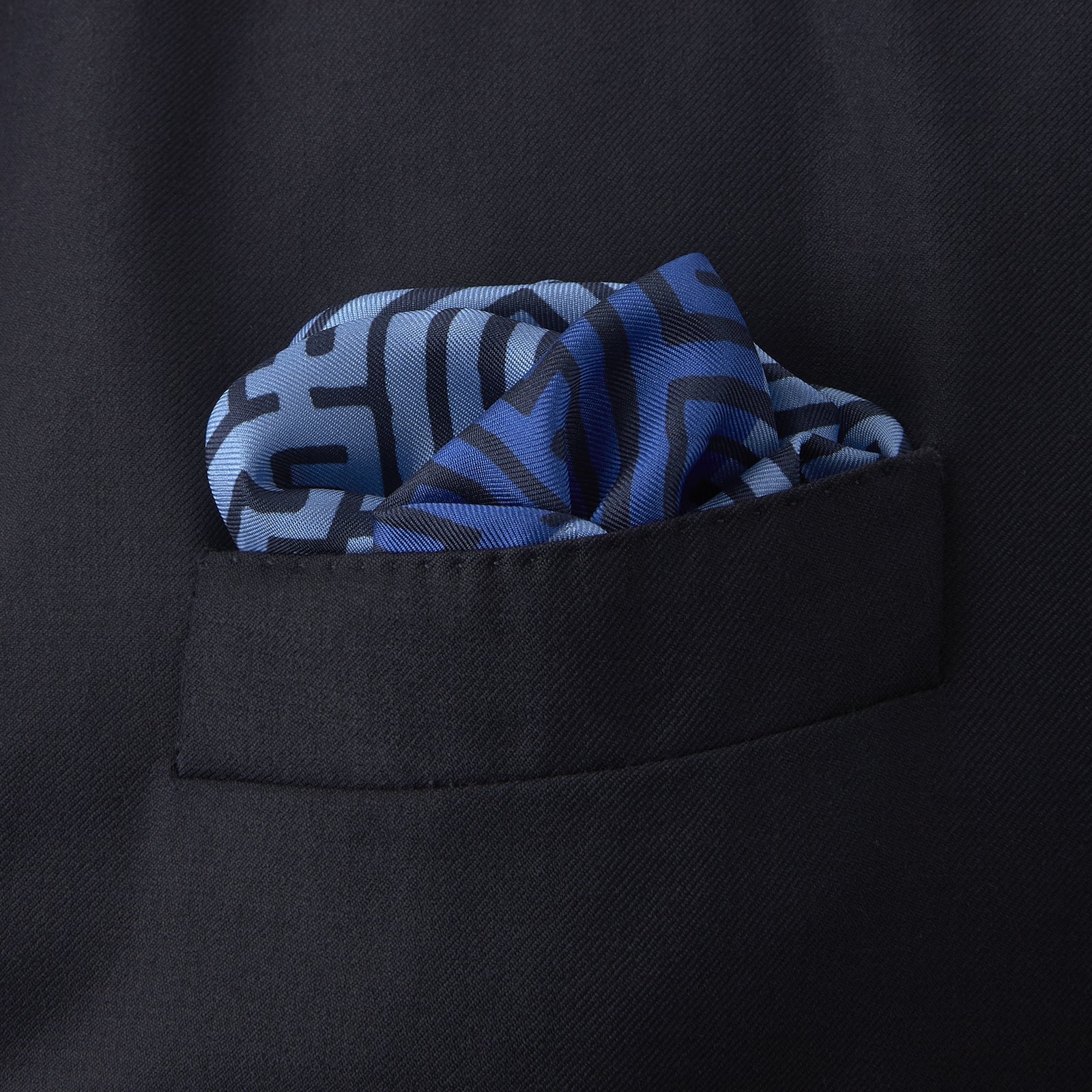 View 4 of product The Blue Maze Silk Pocket Square by Turnbull & Asser features a geometric maze-inspired pattern and central logo, with a folded corner for an artful touch.