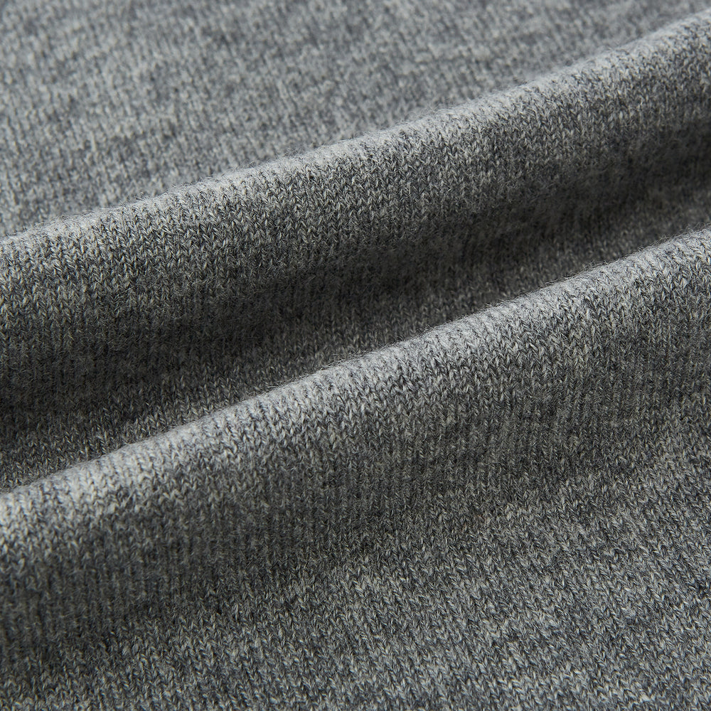 The Turnbull & Asser Plain Grey Cashmere Knitted Scarf is shown draped against a white background, highlighting its soft luxury and timeless appeal.