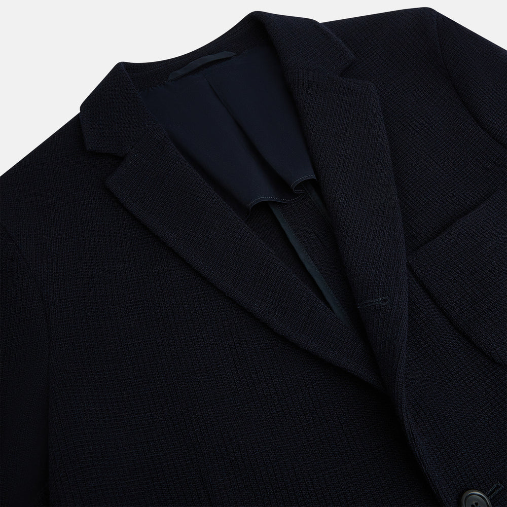 The Turnbull & Asser Navy Knitted Cambridge Blazer features a single-breasted design with three front patch pockets and two buttons, shown against a plain white background.