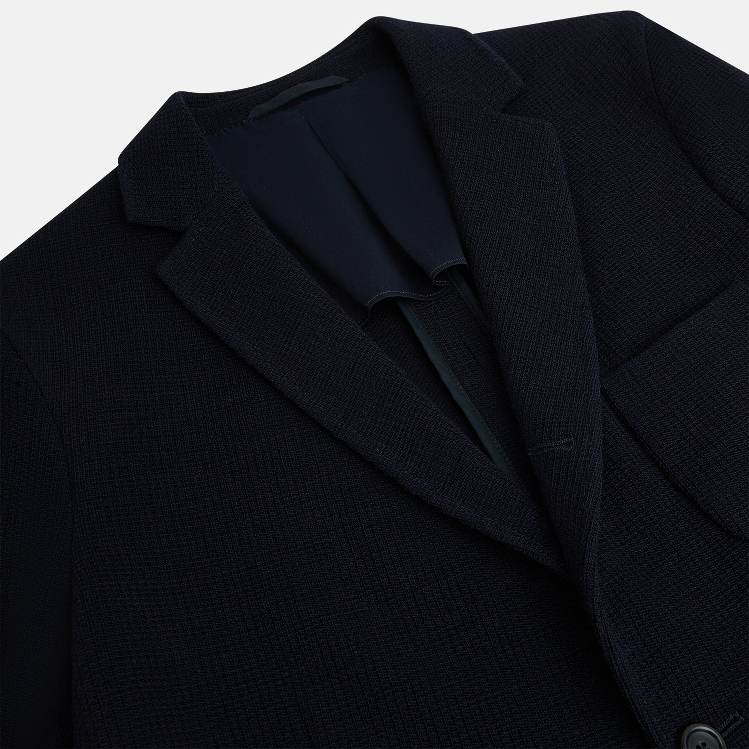View 2 of product The Turnbull & Asser Navy Knitted Cambridge Blazer features a single-breasted design with three front patch pockets and two buttons, shown against a plain white background.