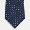 View 3 of product The Turnbull & Asser Navy and White Geometric Silk Tie, featuring a micro pattern of light blue and white squares, is displayed rolled up on a plain white background.