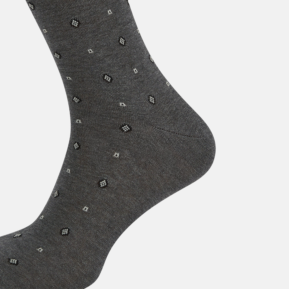 The Grey Patterned Mid-Length Socks by Turnbull & Asser are crafted from soft Egyptian cotton, with a ribbed cuff and small white diamond shapes on a grey background.