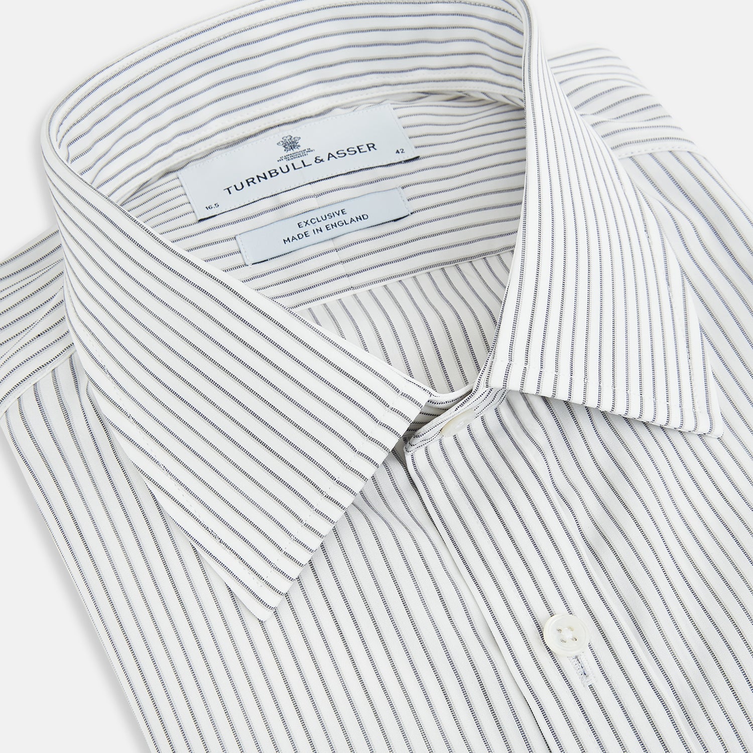 View 2 of product The Navy Music Stripe Mayfair Shirt by Turnbull & Asser features thin vertical blue and white stripes, a classic T&A collar, and long sleeves, shown on a plain white background.
