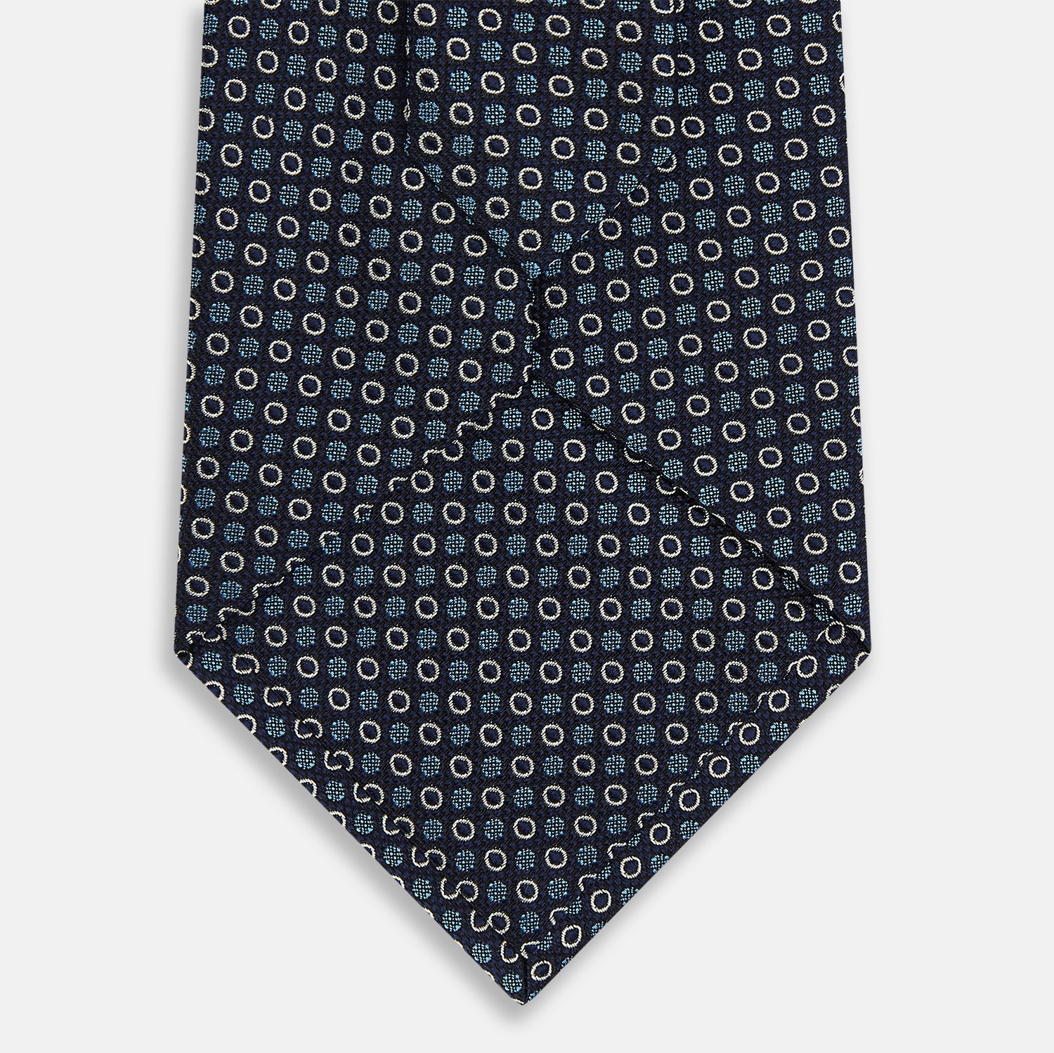 View 3 of product The Turnbull & Asser Blue and Cream Circle Silk Tie features a navy base with a repeating pattern of light blue and cream circles, shown on a plain white background for classic sophistication.