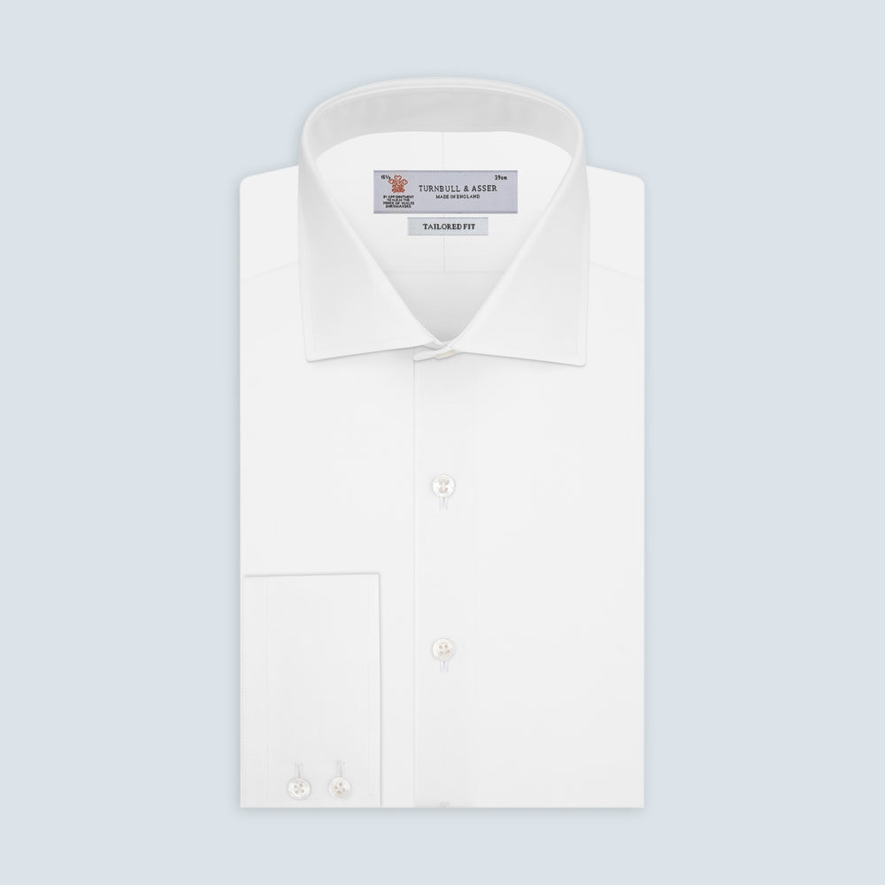 A Turnbull & Asser Tailored Fit Two-Fold 120 White Cotton Shirt with a Kent collar and 2-button cuffs is neatly folded against a light blue background, displaying the brand label inside the collar.