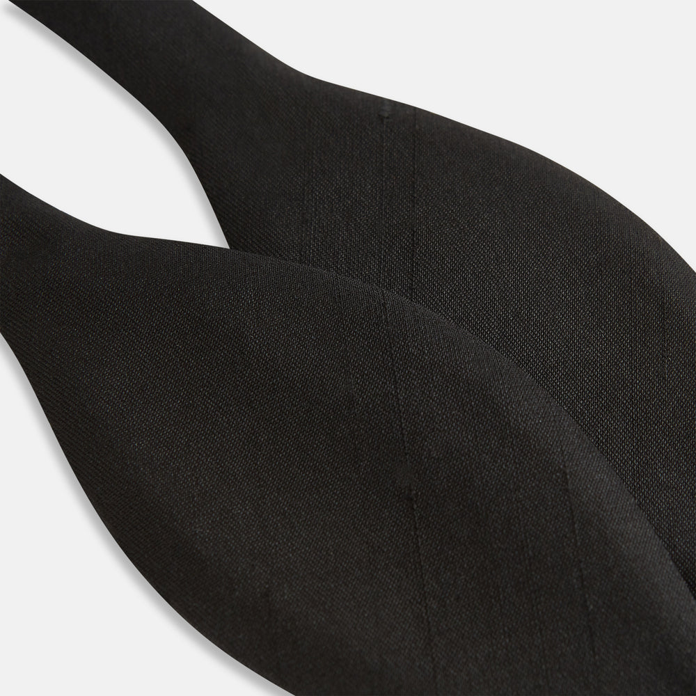 The Casino Royale Shantung Silk Bow Tie by Turnbull & Asser, as seen on James Bond, features a classic shape in black silk and is set against a plain white background—a timeless gentleman’s accessory.