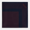 View 3 of product The Turnbull & Asser Navy and Red Dot Silk Pocket Square features a dark navy blue base with small red polka dots on the border and inner pattern, all handmade and neatly folded.