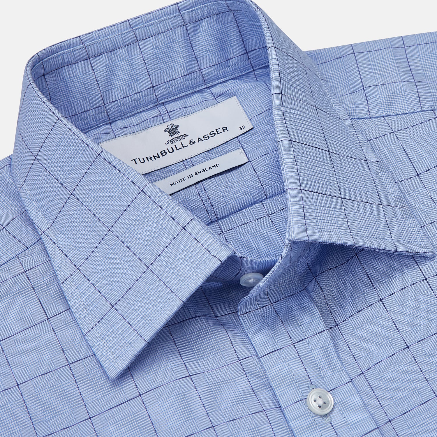View 2 of product The Blue Prince of Wales Check Mayfair Shirt by Turnbull & Asser is a light blue formal long-sleeve shirt with a subtle check pattern, button-down front, and buttoned cuffs, shown laid flat on a white background.