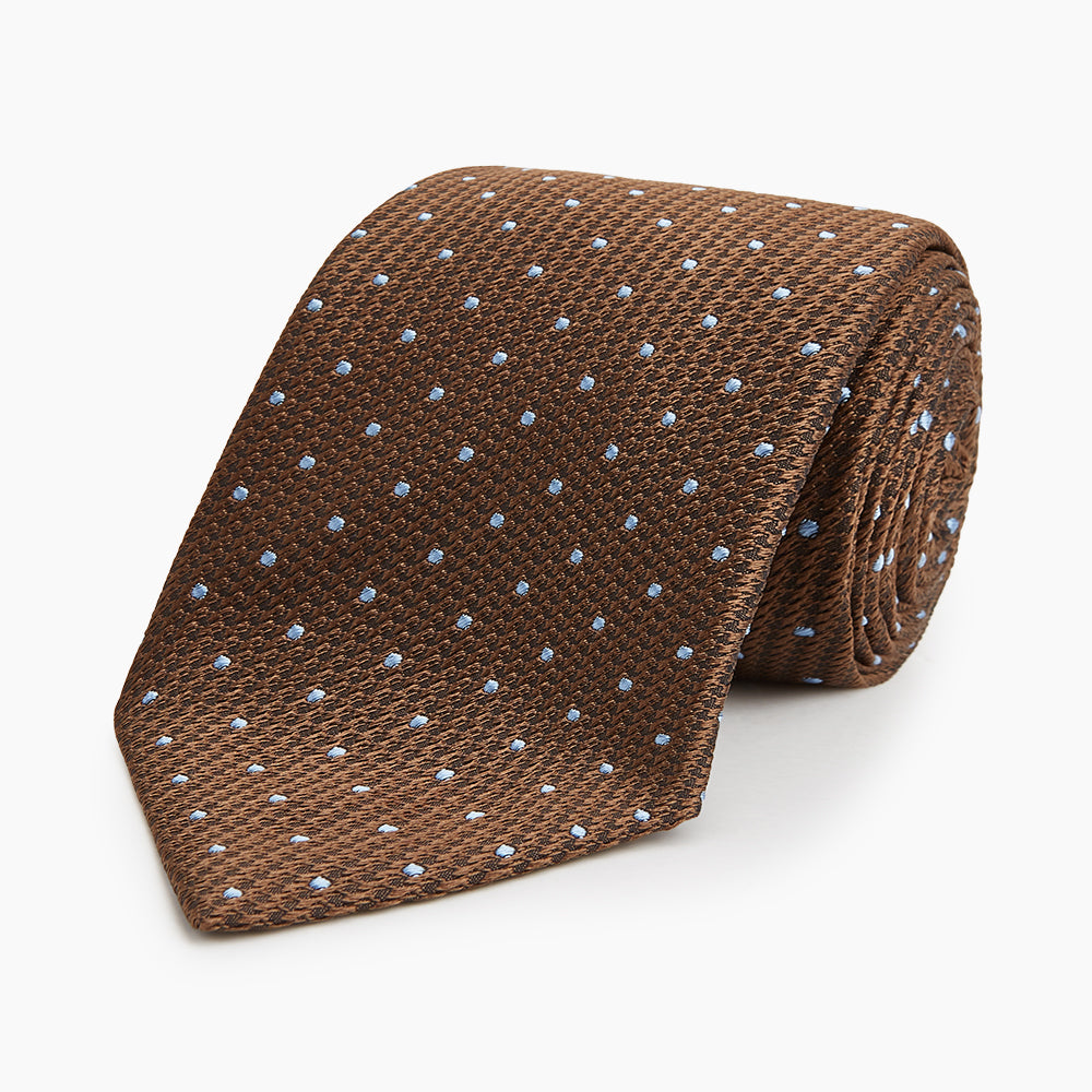 The LACE ON TONE SPOT EARTH RIVER TIE by Turnbull & Asser is a brown woven tie with small light blue dots, shown rolled up on a white background—a stylish accessory for formal outfits.