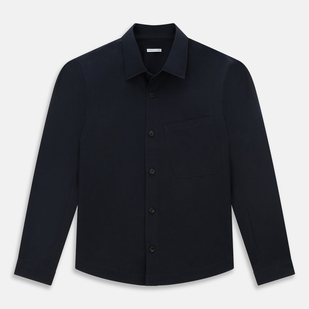 The Midnight Blue Hyde Overshirt by Turnbull & Asser is a plain, long-sleeve shirt in dark navy sanforised cotton with a single chest pocket, spread collar, and black buttons, shown laid flat on a white background.