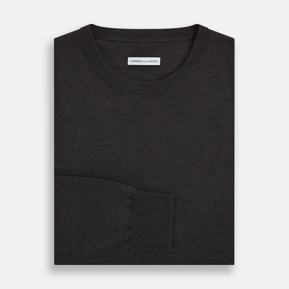 The Turnbull & Asser Charcoal Grey Fine Merino Round Neck Jumper for men features long sleeves, ribbed cuffs, hem, and collar. Displayed on a white background, this classic knitwear piece has a plain design with no visible logos or patterns.
