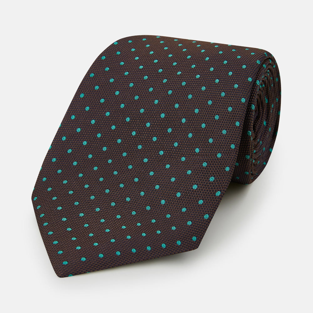 The Turnbull & Asser Turquoise and Forest Green Micro Dot Silk Tie is rolled up, showcasing evenly spaced micro dots on silk, displayed against a plain white background.