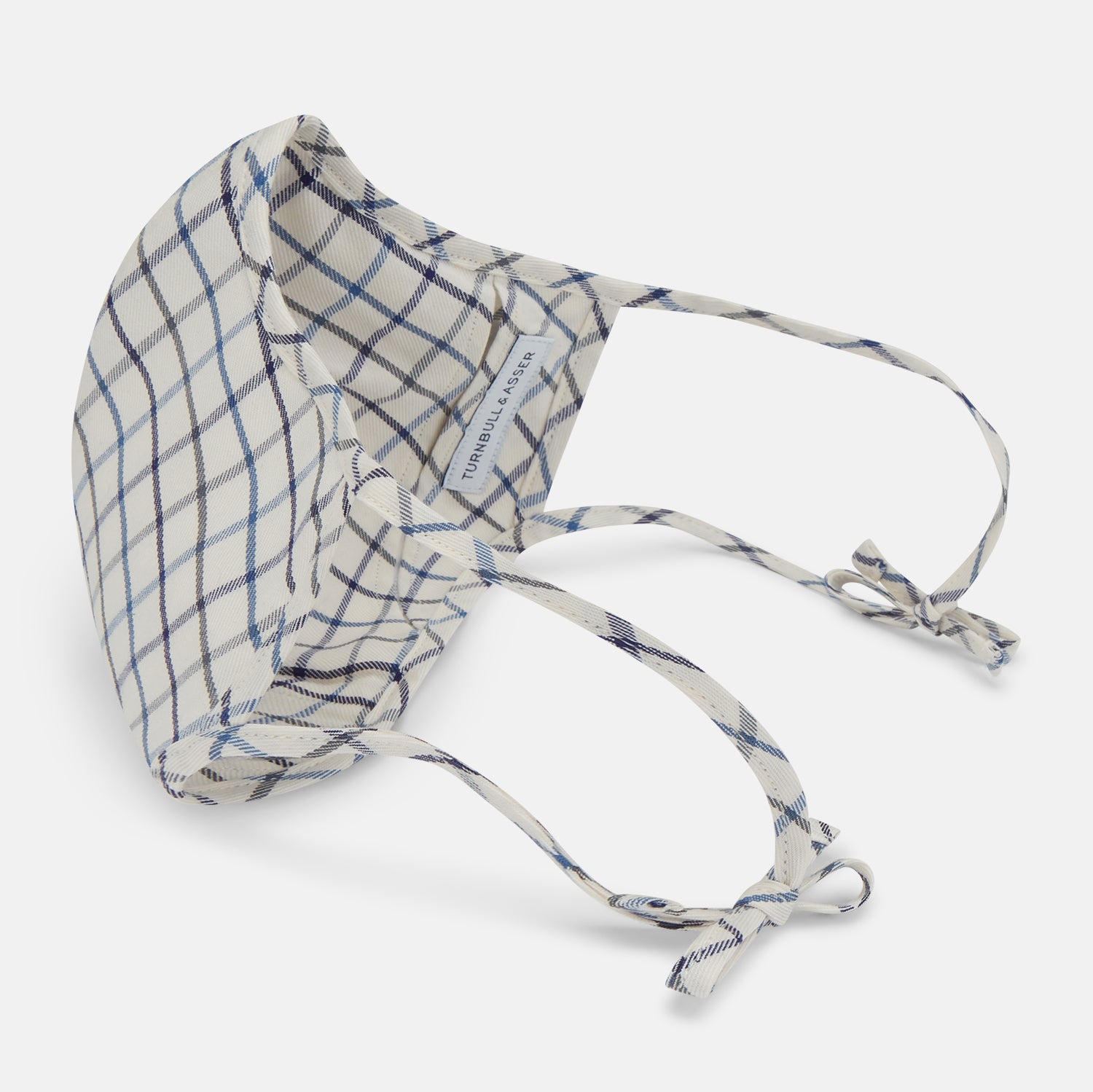 View 4 of product The Turnbull & Asser Check Blue Multi Commuter Mask features a blue plaid design, adjustable fabric ear loops tied in bows, and comes with 3 Viroformula™ filters. Laid flat on a white background.