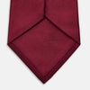 View 4 of product A close-up of the Turnbull & Asser HORIZONTAL TWILL BURGUNDY TIE, a textured men's accessory, rolled up and displayed on a plain white background.